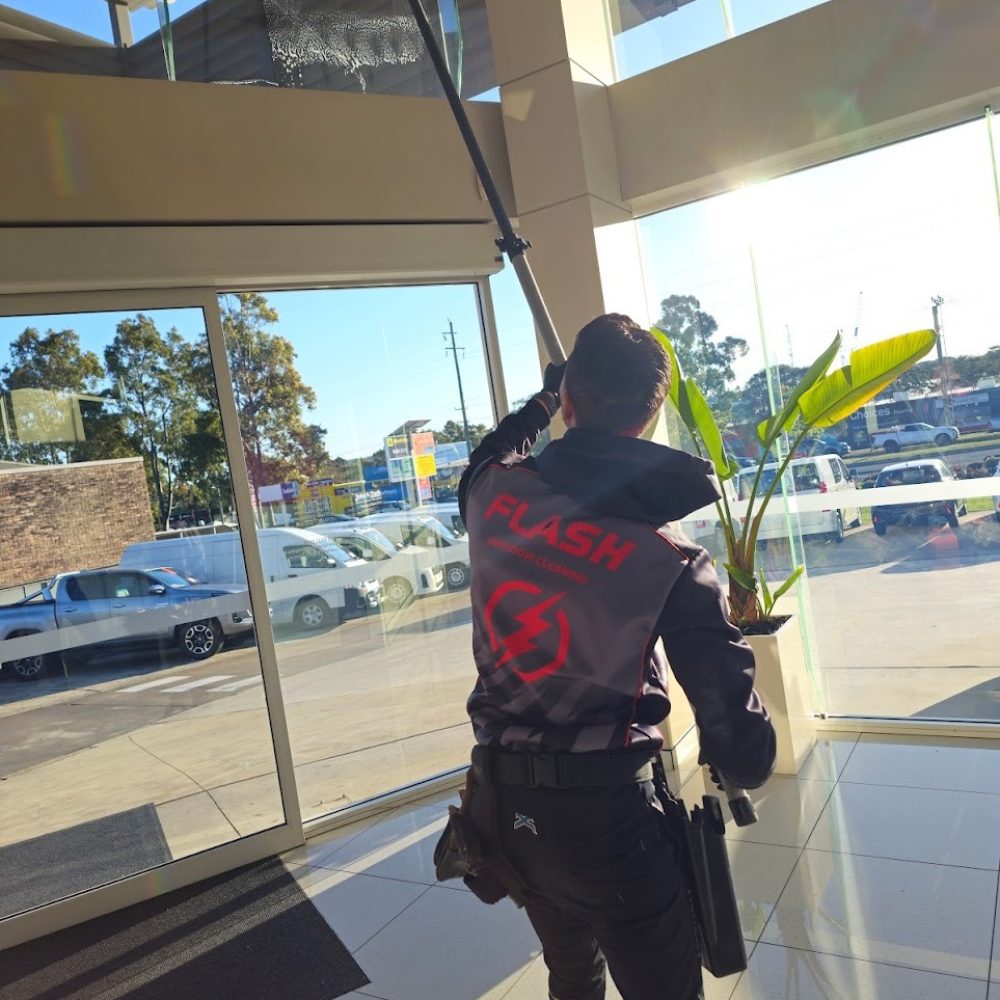 Flash window cleaning using a telescopic pole to clean the inside of a car dealership, toyota